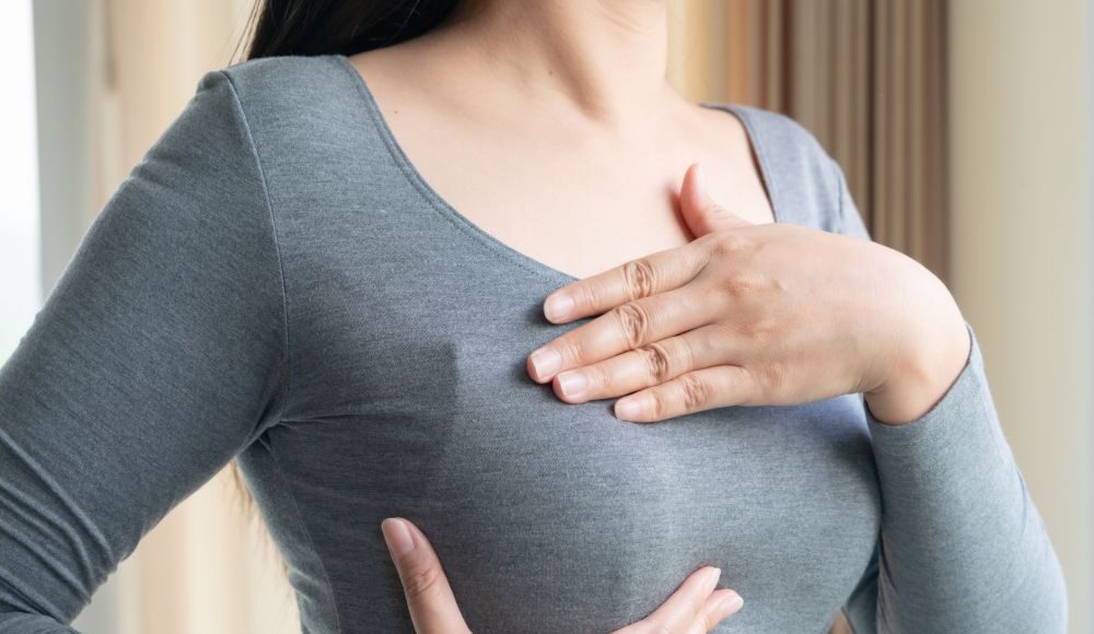 Woman hand checking lumps on her breast for signs of breast cancer. Women healthcare concept.